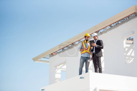 Photo for Construction engineer and architect team working together with blueprints discuss onthe rooftop outdoor at construction site. - Royalty Free Image