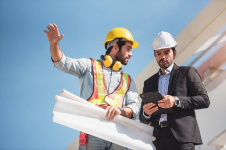 Photo for Construction engineer and architect team working together with blueprints discuss onthe rooftop outdoor at construction site. - Royalty Free Image