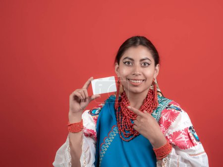 ecuadorian latina fille tenant une carte de crédit et pointant avec l'autre, sur fond rouge