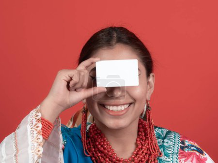 chica latina ecuatoriana sonriente mostrando una tarjeta de crédito a nivel de los ojos