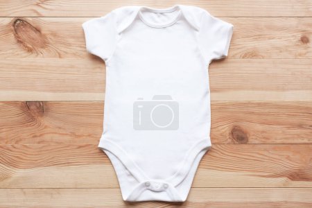 Téléchargez les photos : Maquette de body bébé blanc sur fond bois. Modèle de vêtements de bébé vierges, plat. - en image libre de droit