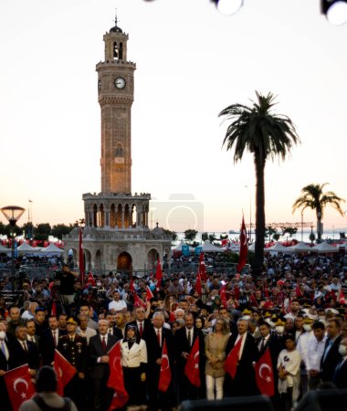 Foto de Izmir, Turquía - 15 de julio de 2022: 15 de julio Día de la Democracia en Turquía Izmir. Poeple sosteniendo banderas turcas en la plaza Konak en Izmir y frente a la histórica torre del reloj. Gobernador de Izmir Yavuz Selim Kosger está en el marco - Imagen libre de derechos