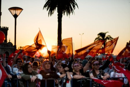 Foto de Izmir, Turquía - 15 de julio de 2022: 15 de julio Día de la Democracia en Turquía Izmir. Poeple sosteniendo banderas turcas en la plaza Konak en Izmir y frente a la histórica torre del reloj. - Imagen libre de derechos