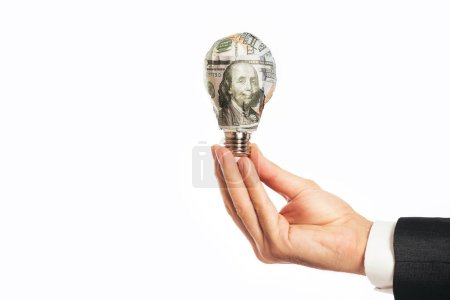 Téléchargez les photos : Main d'homme d'affaires tenant une ampoule qui enveloppait un billet de 100 dollars sur un fond blanc. - en image libre de droit