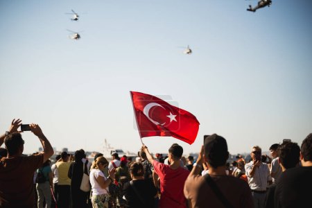 Foto de Izmir, Turquía - 9 de septiembre de 2022: Acercamiento de una bandera turca en el pueblo abarrotado con helicópteros gendarme en el cielo en el día de la libertad de Izmir en Izmir Konak Turquía - Imagen libre de derechos