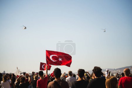 Photo for Izmir, Turkey - September 9, 2022: Close up shot of a  Turkish flag in the crowded people with gendarme helicopters on the sky on the liberty day of Izmir at Izmir Konak Turkey - Royalty Free Image