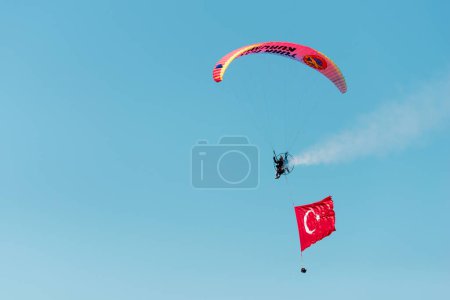 Foto de Izmir, Turquía - 9 de septiembre de 2022: Paramotor jumper on the sky with a huge Turkish flag on the freedom day of Izmir at Izmir Konak Turkey - Imagen libre de derechos