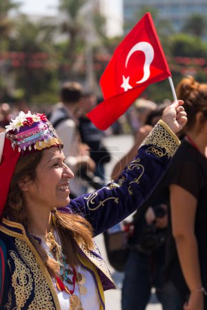 Photo for Izmir, Turkey - September 9, 2022: Woman with traditional cloths holding and waving a Turkish flag in a at the celebrations of liberation day Izmir Turkey at the Republic square. - Royalty Free Image