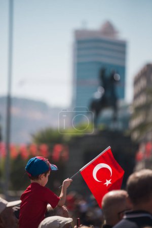 Foto de Izmir, Turquía - 9 de septiembre de 2022: Un niño con una bandera y una camiseta turcas sobre los hombros de un adulto en el día de la liberación de Izmir, Turquía, en la plaza de la República Konak Alsancak. - Imagen libre de derechos