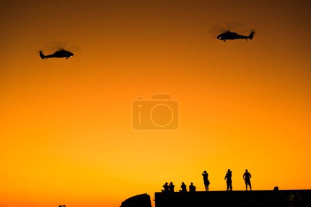 Photo for Izmir, Turkey - September 9, 2022: Silhouette of  Turkish gendarme helicopters on the sky with some photographers  on the liberty day of Izmir at Izmir Konak Turkey - Royalty Free Image
