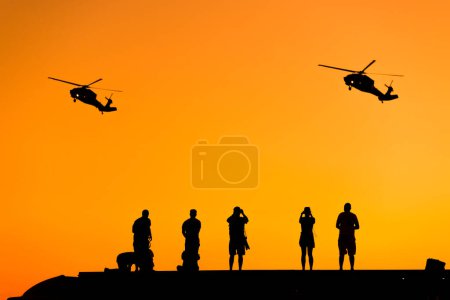 Photo for Silhouette of some photographer people taking photo of helicopters on sunset. - Royalty Free Image