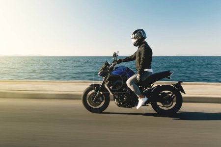 Téléchargez les photos : Vue latérale d'une moto motocycliste course moto sur fond marin avec flou de mouvement - en image libre de droit