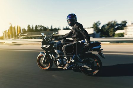 Photo for Side view of a motorcycle rider riding race motorcycle like sitting on a chair on the highway with motion blur. - Royalty Free Image