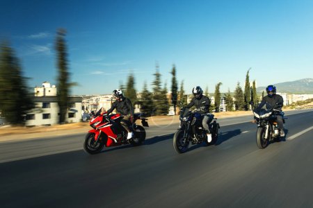 Foto de Tres motociclistas de carrera superdeportiva van uno al lado del otro en la carretera con desenfoque de movimiento. - Imagen libre de derechos