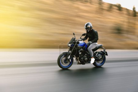 Téléchargez les photos : Vue latérale d'un motocycliste circulant sur la route avec flou de mouvement. - en image libre de droit