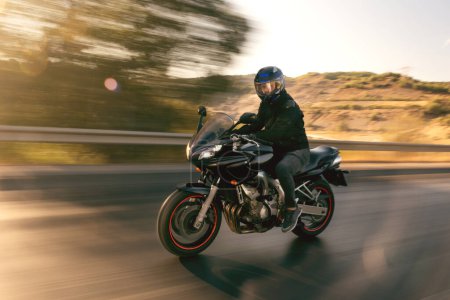 Side view of a motorcycle rider riding on the highway with motion blur. 