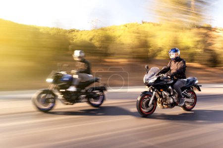 Foto de Dos motociclistas de carrera superdeportivos que van uno al lado del otro en la carretera con desenfoque de movimiento. - Imagen libre de derechos