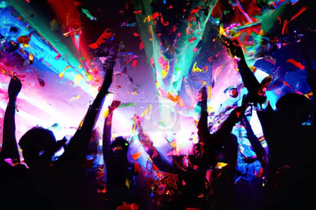 Photo for Silhouette people in a club with colorful spot lights and confetis - Royalty Free Image