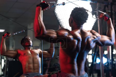 20s Masculino negro ejercitando los músculos posteriores delt y espalda con máquina de cable