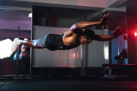 Foto de 20s negro macho haciendo vuelo flexiones en un gimnasio. - Imagen libre de derechos