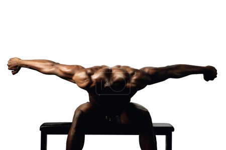 Foto de Retrato de un macho musculoso negro sentado en un banco y brazos abiertos dos caminos laterales sobre un fondo blanco - Imagen libre de derechos