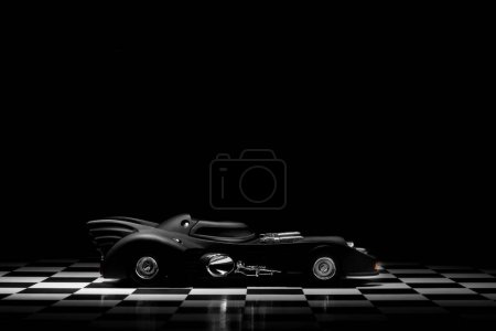 Photo for Izmir, Turkey - March 15, 2023: 1989 Batmobile toy model car on a chequered ground and black background. - Royalty Free Image