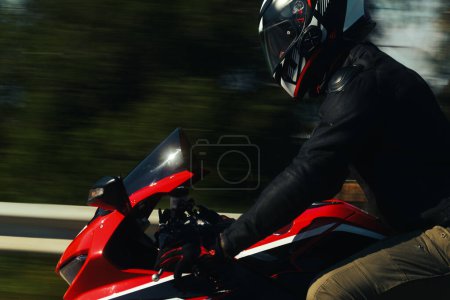 Téléchargez les photos : Vue latérale d'un motard roulant moto de course rouge sur l'autoroute avec flou de mouvement. - en image libre de droit