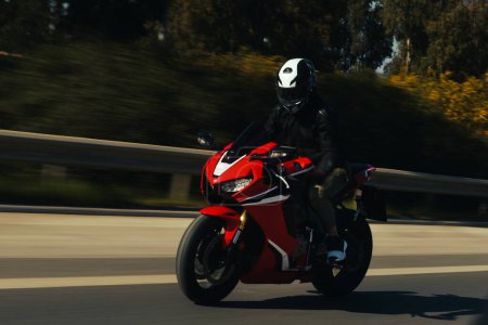 Téléchargez les photos : Vue latérale d'un motocycliste circulant sur la route avec flou de mouvement. - en image libre de droit