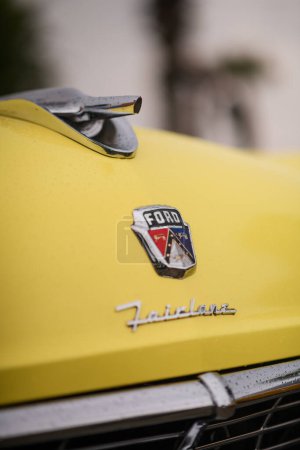 Téléchargez les photos : Izmir, Turquie - 3 juin 2023 : Plan rapproché de l'emblème sur le devant d'une Ford Fairlane 1956 jaune et noire, scintillante de gouttes de pluie, lors de l'IZKOD Classic Car Meet à Buca Pond. - en image libre de droit