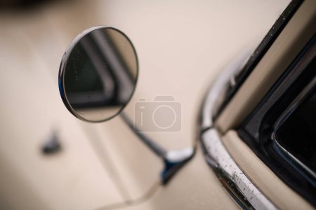 Foto de Izmir, Turquía - 3 de junio de 2023: Primer plano de un espejo lateral redondo en un coche clásico de color beige, adornado con gotas de lluvia, en un evento de coches clásicos - Imagen libre de derechos