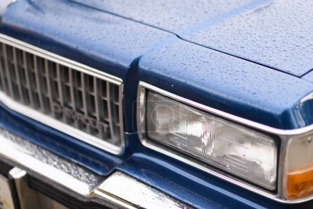 Téléchargez les photos : Izmir, Turquie - 3 juin 2023 : Gros plan sur le phare unique d'une Chevrolet Caprice bleue, peut-être un modèle 1978, orné de gouttes de pluie - en image libre de droit