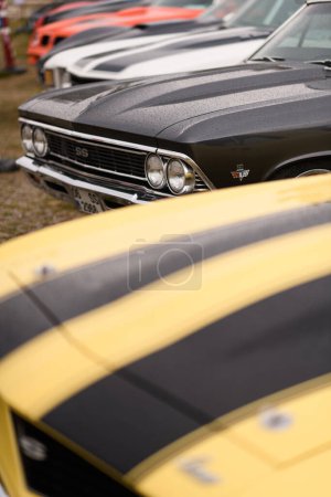 Photo for Izmir, Turkey - June 3, 2023: Front view of a black Chevrolet Chevelle SS 350 amid raindrops and other classic cars at a car gathering - Royalty Free Image