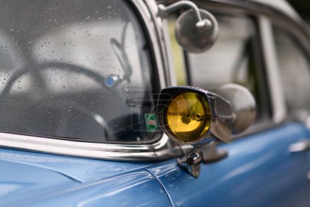 Téléchargez les photos : Izmir, Turquie - 3 juin 2023 : Gros plan de la lumière du signal sur le miroir d'une Chevrolet 1954 bleu ciel, décorée de gouttes de pluie - en image libre de droit
