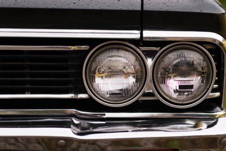 Photo for Izmir, Turkey - June 3, 2023: Close-up of the headlight on a black Chevrolet Chevelle SS covered in raindrops - Royalty Free Image