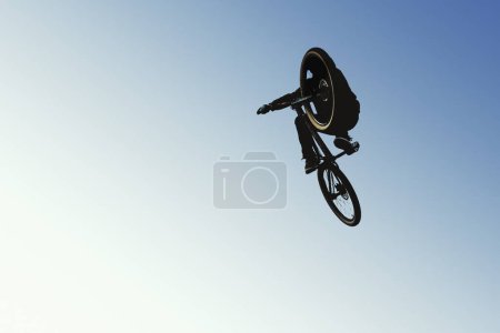 Téléchargez les photos : Un cycliste au milieu du saut, en silhouette contre le ciel ouvert. L'image capture le frisson du vélo - en image libre de droit
