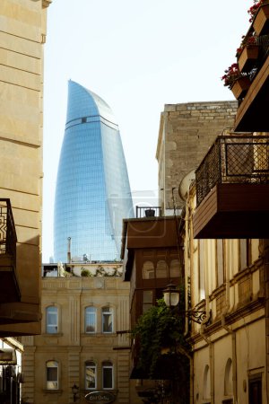 Foto de Bakú, Azerbaiyán - 25 de junio de 2023: Un vistazo a una Torre de la Llama, un icono moderno de Bakú, visto a través de los edificios históricos de Icheri Sheher, el corazón de la antigua Bakú - Imagen libre de derechos
