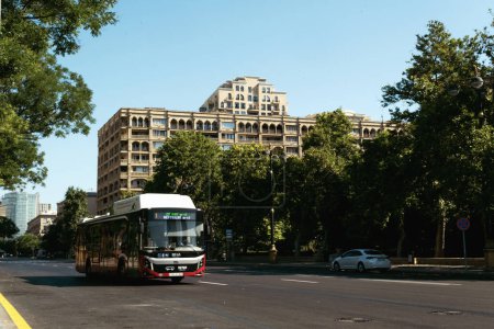 Téléchargez les photos : Bakou, Azerbaïdjan - 26 juin 2023 : Un bus passe dans les rues de Bakou, avec un bâtiment historique près de la Maison du Gouvernement en arrière-plan - en image libre de droit