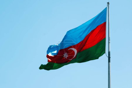 Foto de Una vibrante foto de la bandera de Azerbaiyán ondeando orgullosamente contra un cielo despejado, encarnando el espíritu y la resiliencia de la nación - Imagen libre de derechos