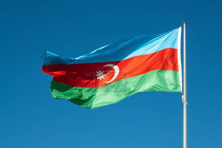 Foto de Una vibrante foto de la bandera de Azerbaiyán ondeando orgullosamente contra un cielo despejado, encarnando el espíritu y la resiliencia de la nación - Imagen libre de derechos