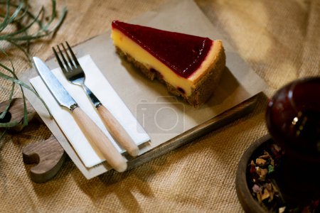 Photo for A close-up capture of a strawberry cheesecake slice on a rustic wooden board, with the gentle embrace of ambient candlelight, presented on a burlap tablecloth. - Royalty Free Image