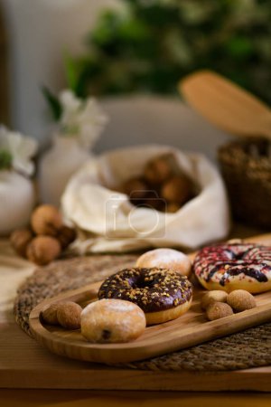 Photo for A close-up of donuts and cookies on a wooden tray. In the background, walnuts nestle in a white cloth, bathed in soft, ambient light. - Royalty Free Image