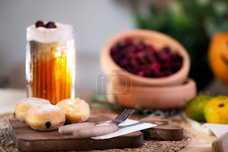 Photo for Chocolate-filled cookie with cutlery on a cutting board, served with frothy apple juice, red blackberries, tangerines, and a jack o'lantern in the backdrop. - Royalty Free Image