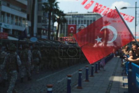 Téléchargez les photos : Cette photo saisissante prise le 30 août 2023, à Izmir Kordon, met en évidence un drapeau turc de couleur vive au premier plan. En arrière-plan, légèrement décalé en raison d'une faible profondeur de champ, les soldats peuvent être vus marchant dans un c - en image libre de droit