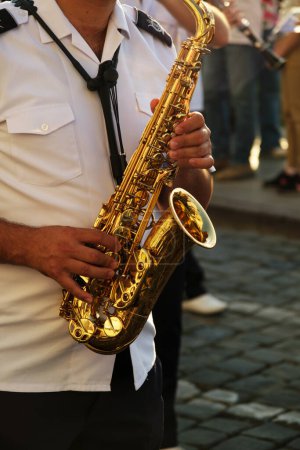 Foto de Izmir, Turquía - 1 de septiembre de 2023: En el corazón de una bulliciosa plaza de la ciudad, el saxofón de un músico dedicado brilla bajo el sol de la tarde, resonando con las armonías de la vibrante vida callejera de Izmir - Imagen libre de derechos