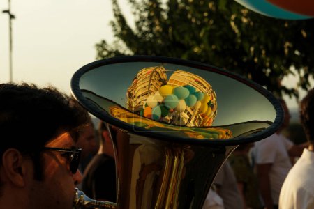 Téléchargez les photos : Le 1er septembre 2023, lors de la procession d'ouverture de la Foire internationale d'Izmir, un musicien joue du tuba. Un gros plan de l'instrument révèle un reflet des bâtiments de la ville et des ballons flottants, fusionnant la musique avec l'atmosphère vibrante - en image libre de droit