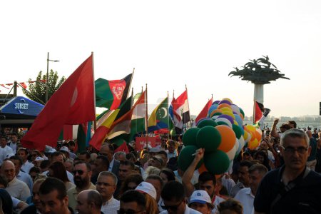 Téléchargez les photos : Izmir, Turquie - 1er septembre 2023 : Des foules agitent des drapeaux de divers pays lors de la marche du cortège d'ouverture de la Foire internationale d'Izmir. La célèbre statue "Cumhuriyet Tree" se dresse en arrière-plan sur la place Cumhuriyet - en image libre de droit