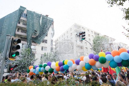 Foto de Izmir, Turquía - 1 de septiembre de 2023: Durante el cortejo de apertura de la Feria Internacional de Izmir, las multitudes caminan por las calles de Alsancak con globos en la mano. Mientras llueve confeti del cielo, un semáforo verde se destaca en el marco - Imagen libre de derechos