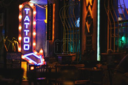 Photo for Izmir, Turkey - September 1, 2023: Nestled in the narrow streets of Alsancak, a tattoo shop stands out with its neon lights spelling "Tattoo" at the entrance, capturing the urban vibe of the area. - Royalty Free Image