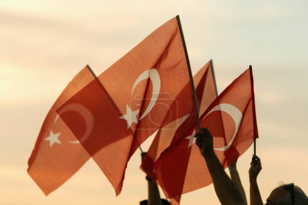 Téléchargez les photos : Izmir, Turquie, le 9 septembre 2023, alors que les couchers de soleil se couchent, quatre individus se tiennent unis, agitant le drapeau turc sur fond de ciel couchant vibrant, symbolisant l'unité et la fierté lors des célébrations du Jour de la Libération. - en image libre de droit