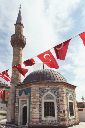 Foto de Izmir, Turquía, 9 de septiembre de 2023: Una vista cautivadora de la histórica mezquita de Konak, adornada con banderas turcas ondeantes, conmemorando la liberación de Izmir. La combinación de esplendor arquitectónico y orgullo nacional es palpable - Imagen libre de derechos